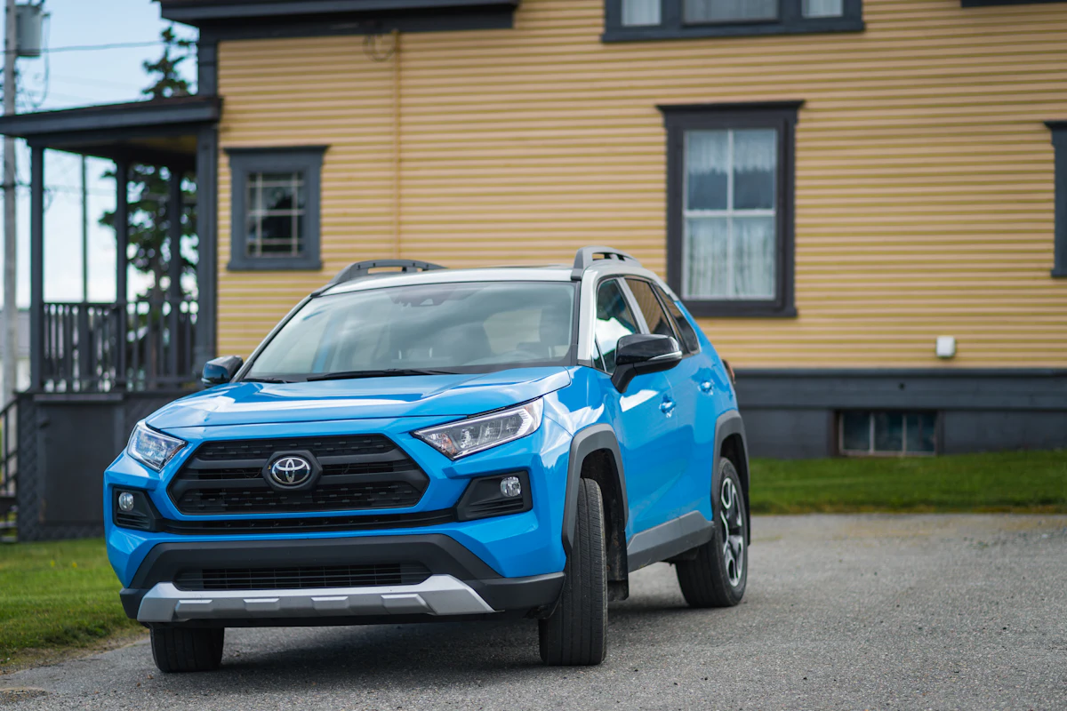 Mavi bir Toyota RAV4, ahşap cepheli bir evin önünde park halinde